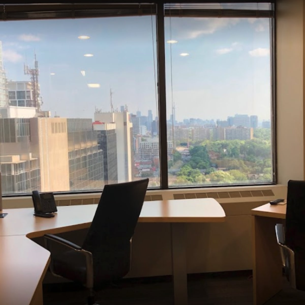 A modern office space with two empty chairs and a large window overlooking a cityscape.