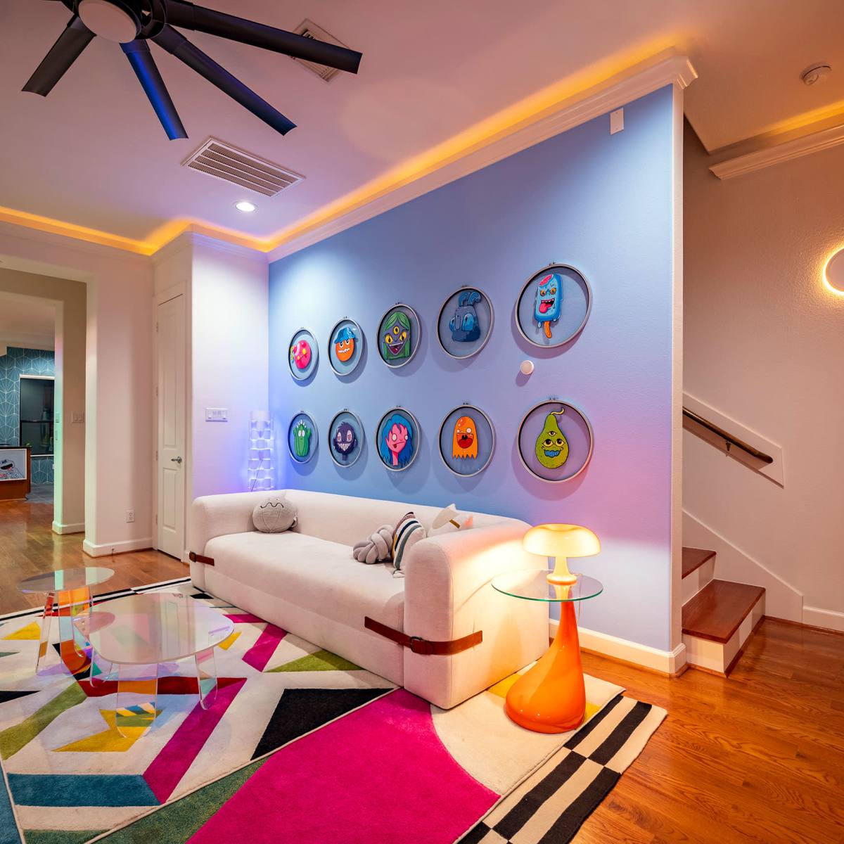 A modern living room with a white sofa, colorful artwork on the wall, and a striped rug.
