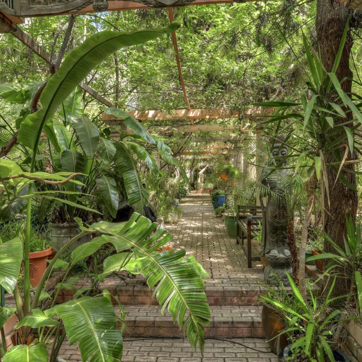 A landscaped garden pathway lined with columns and lush greenery, leading deeper into the space.