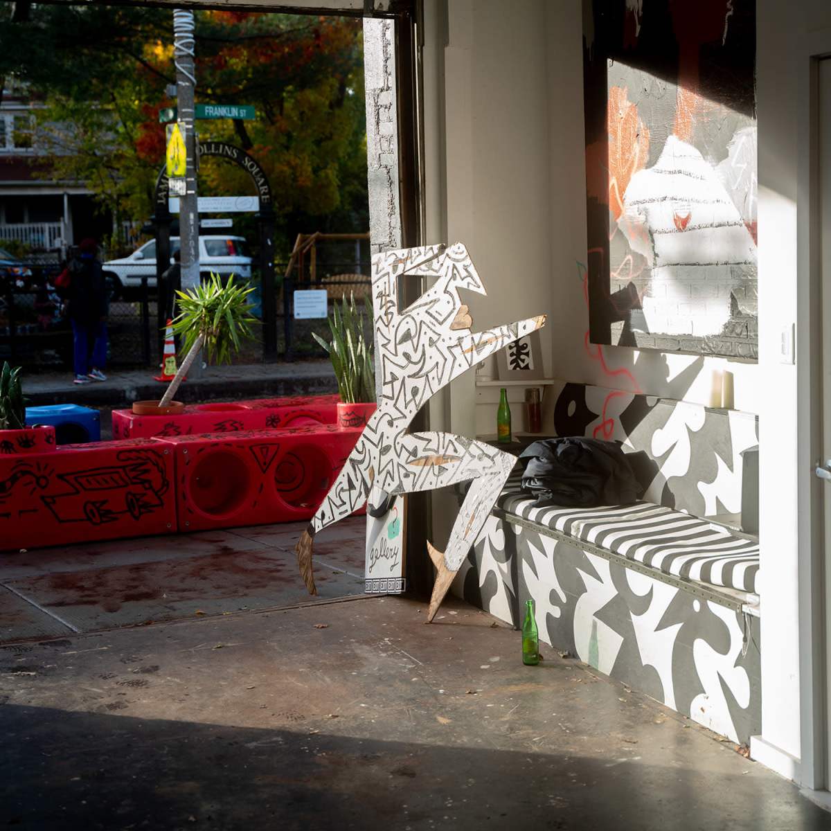 An open space featuring abstract graffiti art, a patterned bench, and a large stylized sculpture.