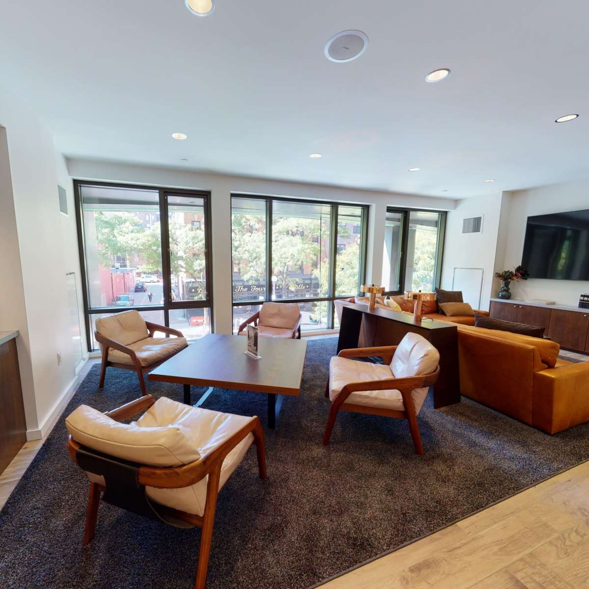 A modern lounge area with leather seating, a coffee table, and large windows that overlook an outdoor space.