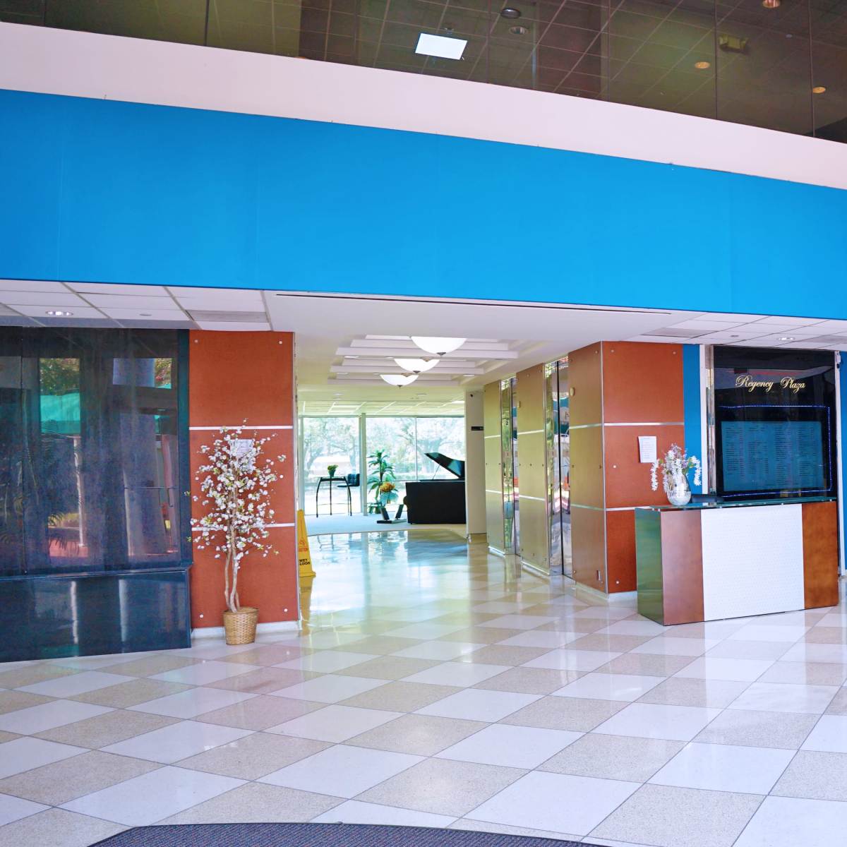 A modern lobby with a tiled floor, glass partitions, and a seating area featuring a table and chairs.