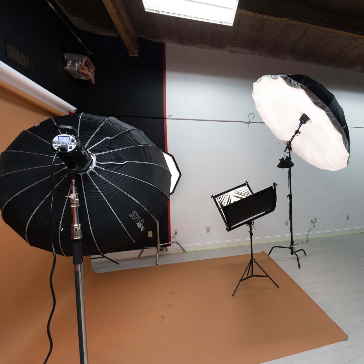 A photography studio with three softbox lights, a backdrop, and a roll-up door.