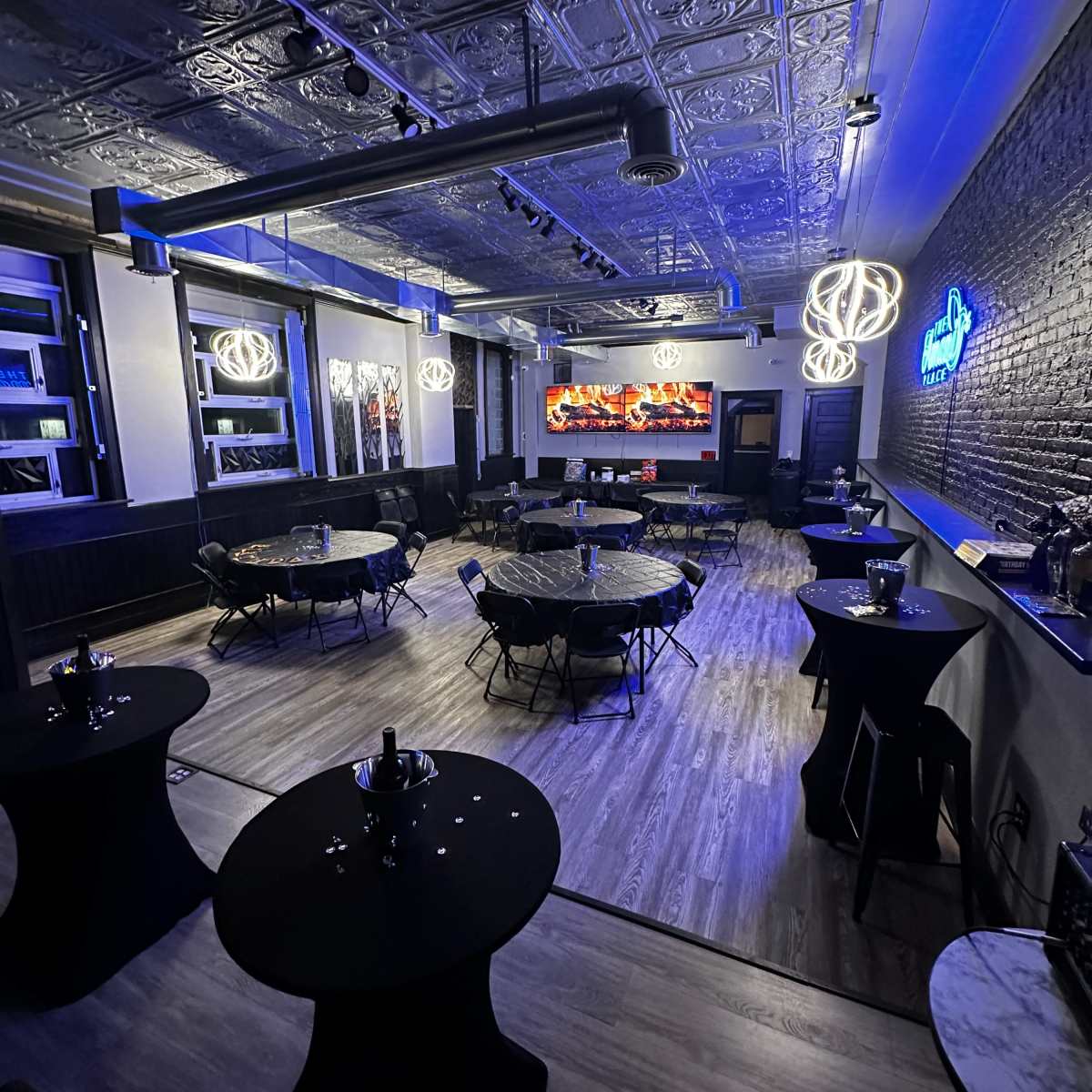 An elegantly arranged event space with round tables, a bar area, and decorative lighting.