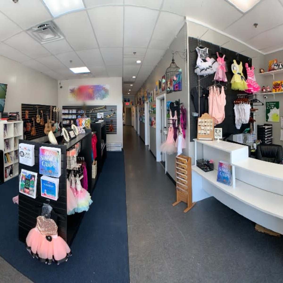 A spacious retail store with displays of colorful clothing and accessories, a reception area, and various artworks on the walls.