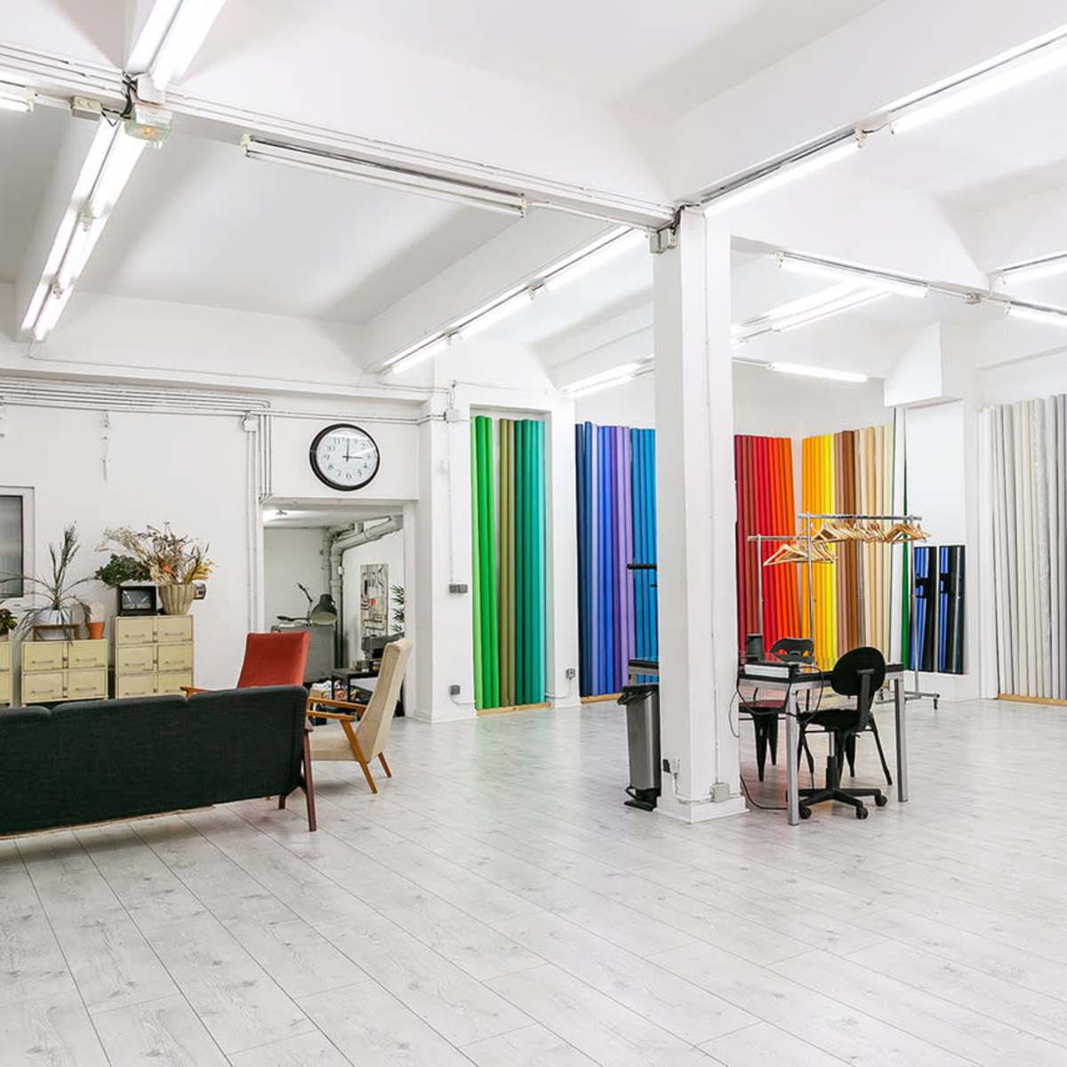 A bright, spacious studio with colorful vertical panels on one wall and a set of mirrors arranged on another.
