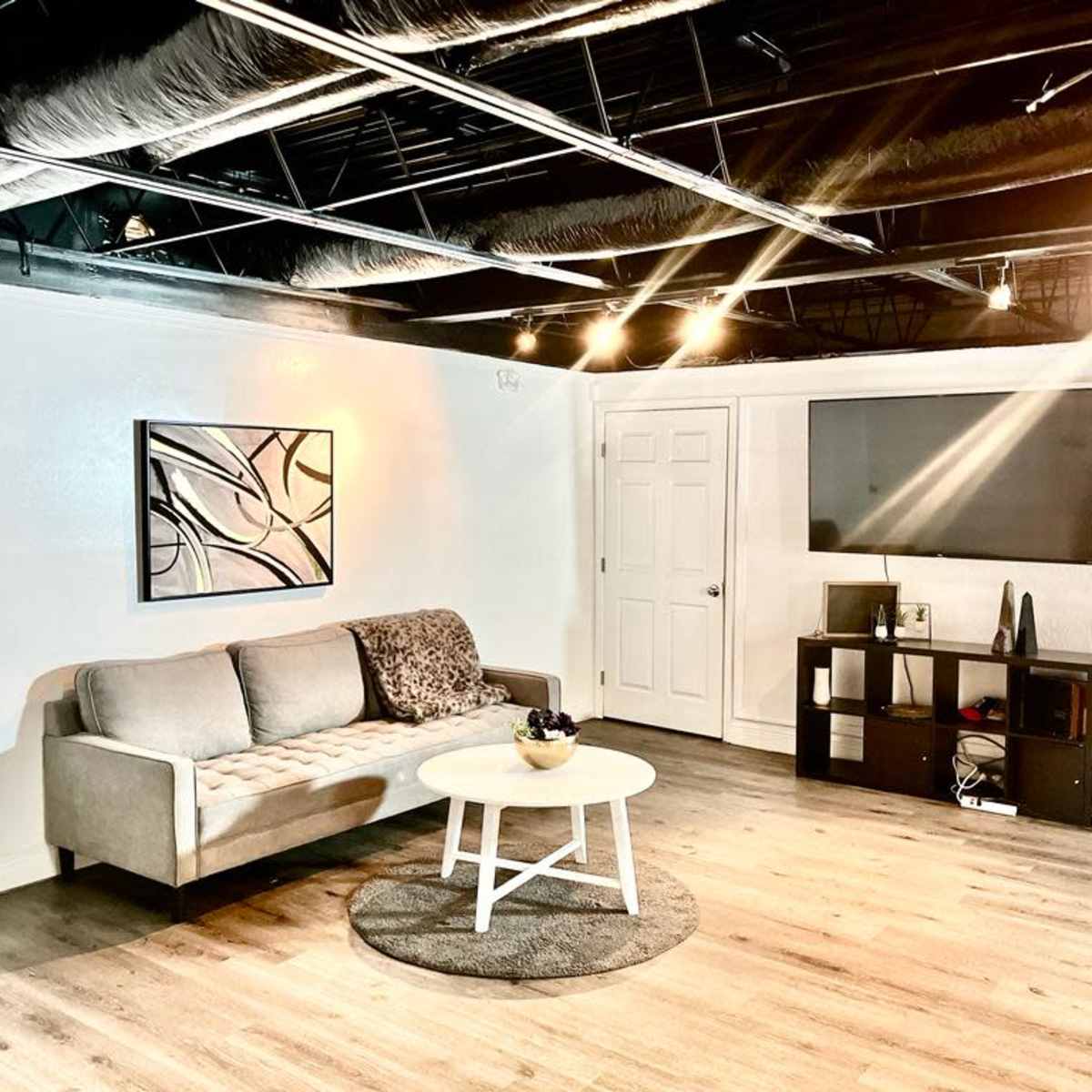 A modern, minimalistic living space with a gray sofa, a round coffee table, and a television mounted on the wall.