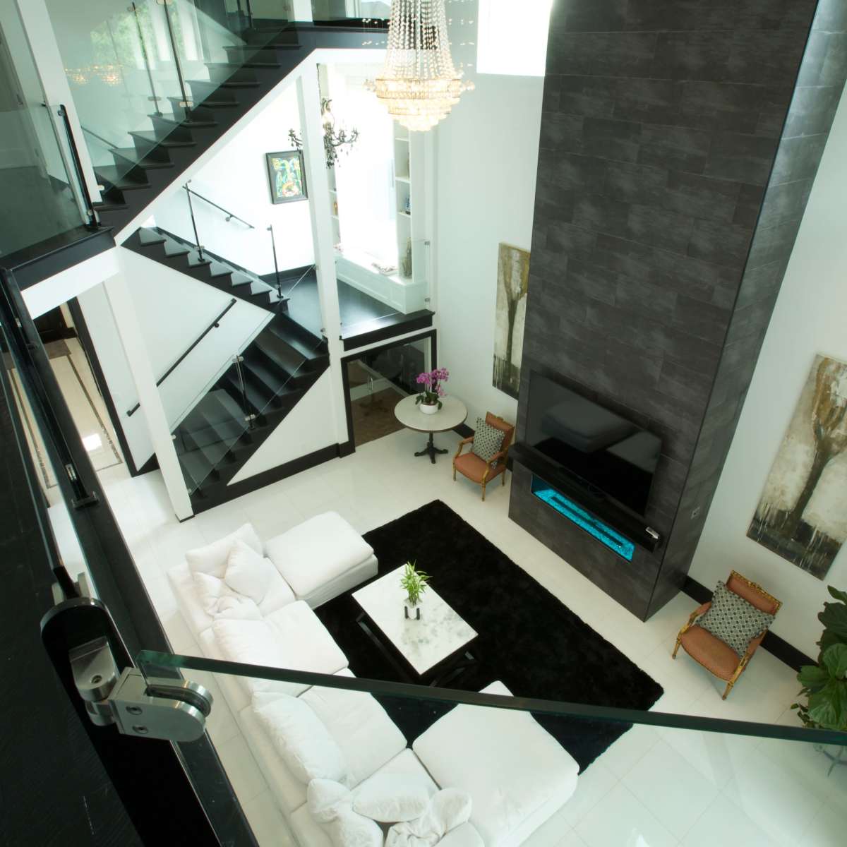 A modern living room with a large white sectional sofa, a coffee table on a black rug, and a tall feature wall with a mounted television.