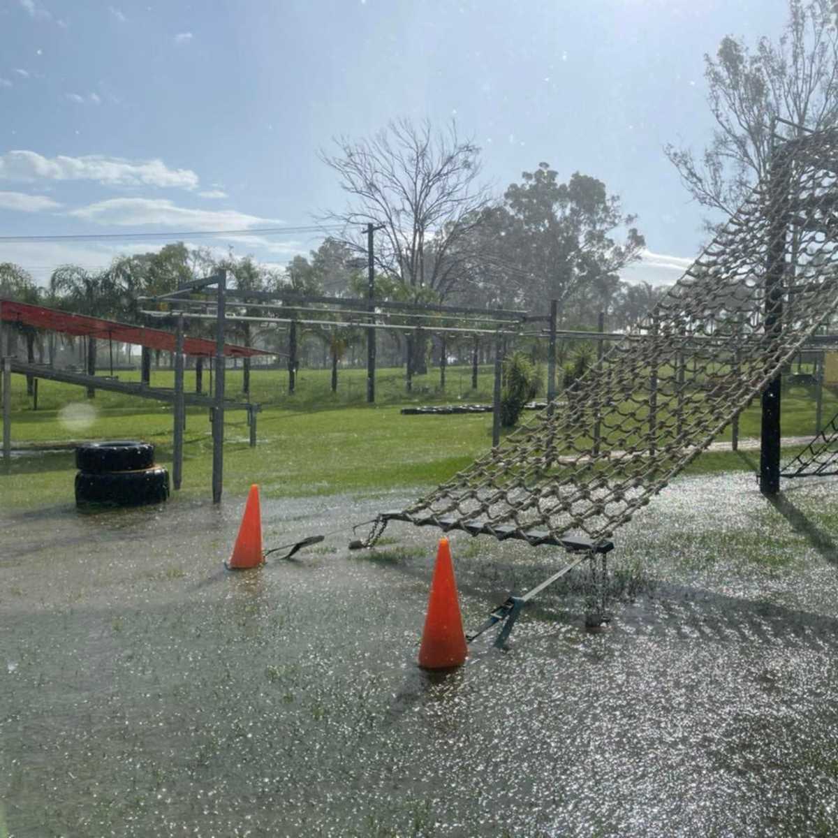 A playground obstacle course is partially submerged in water on a rainy day.