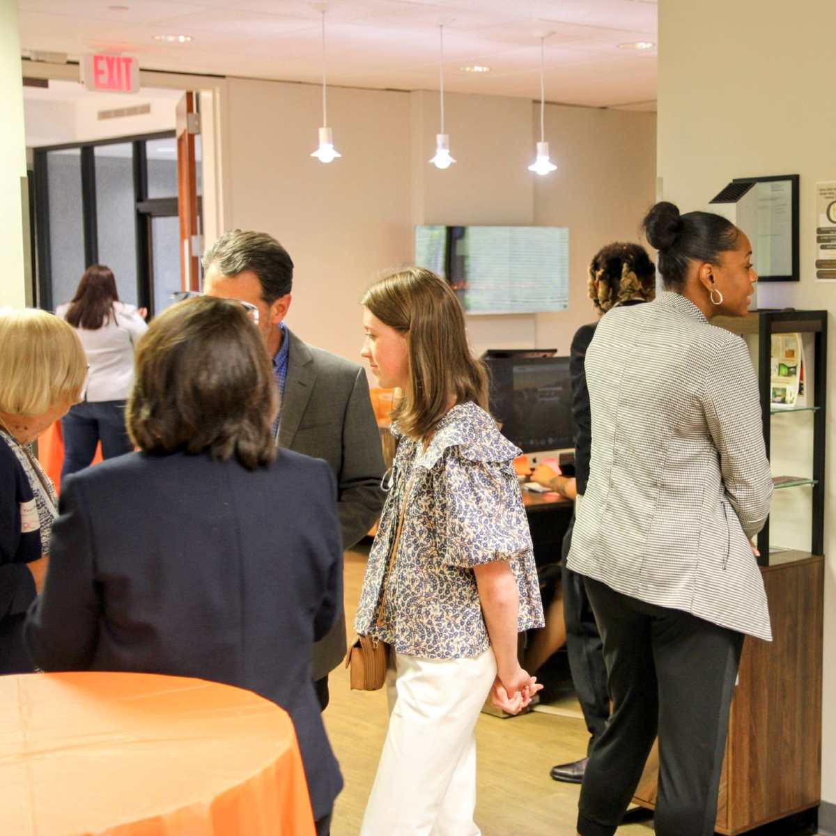 A group of people engage in conversation at a networking event in a modern office setting.