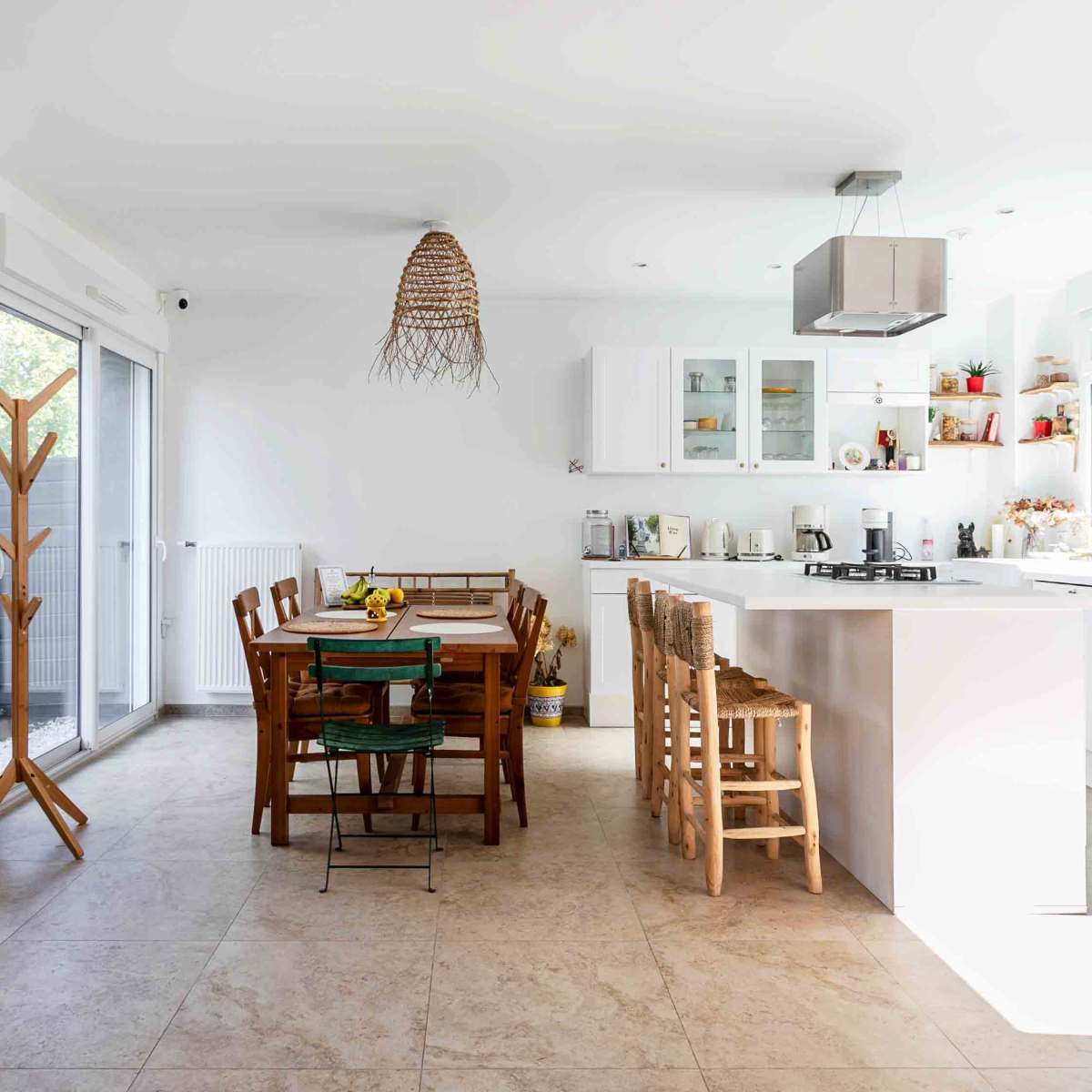 A modern kitchen features a dining table with wooden chairs, light-colored walls, and a bright blue refrigerator.