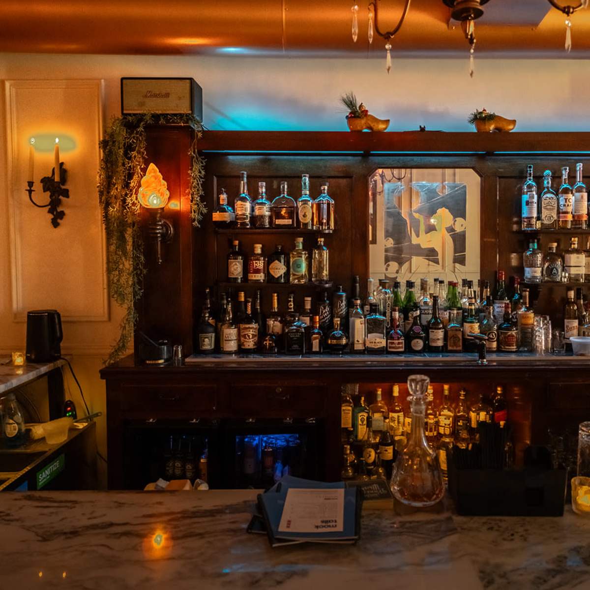 A well-stocked bar with shelves filled with various bottles of alcohol, illuminated by warm lighting.