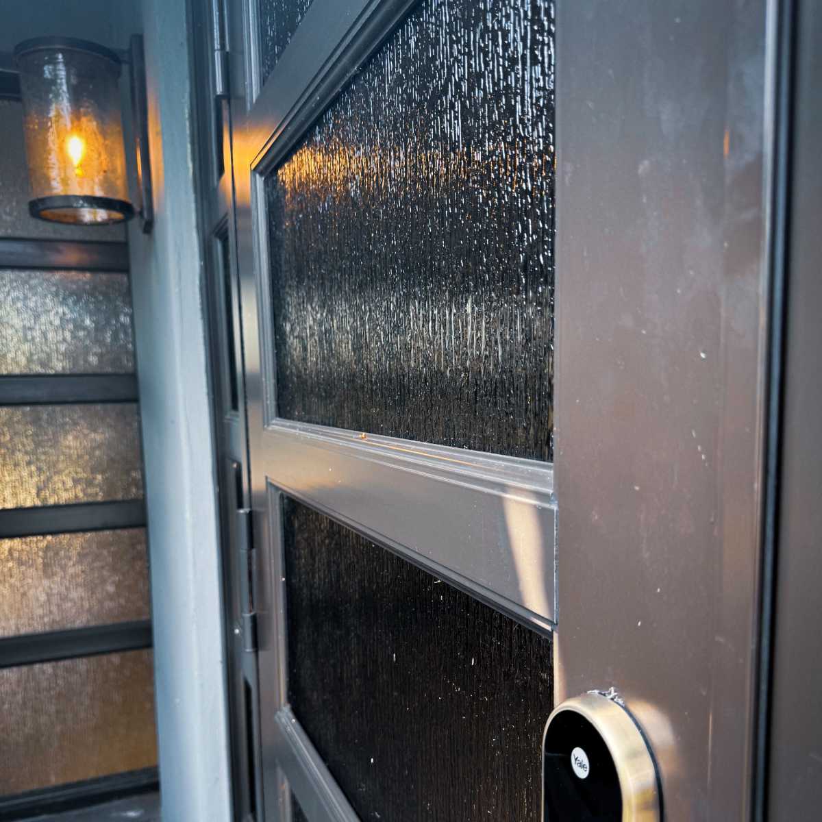 A close-up view of a door with a modern smart lock and a lantern illuminating the entrance area.