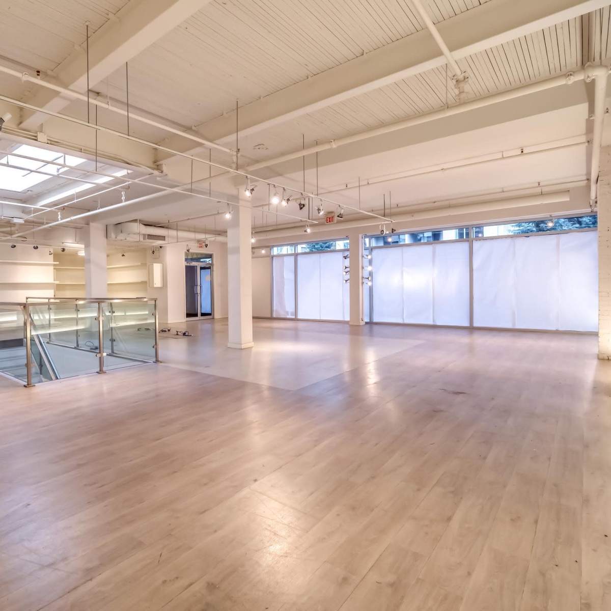 A spacious, well-lit interior of a commercial building with large windows and a glass-railed mezzanine.
