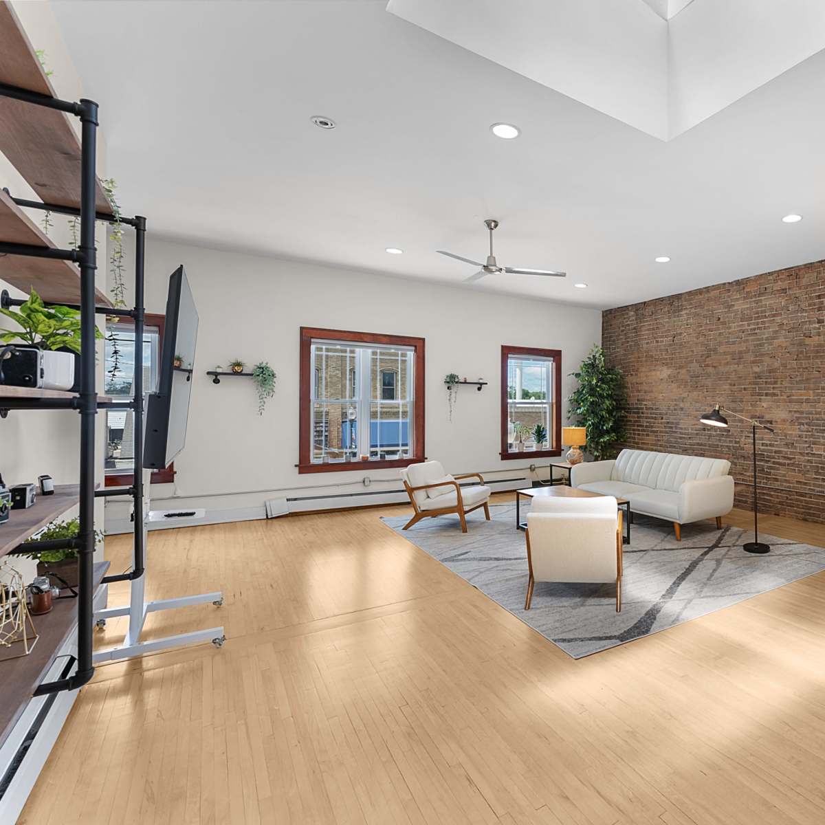 A modern living room with a white sofa, a chair, a wooden door, and a brick accent wall.