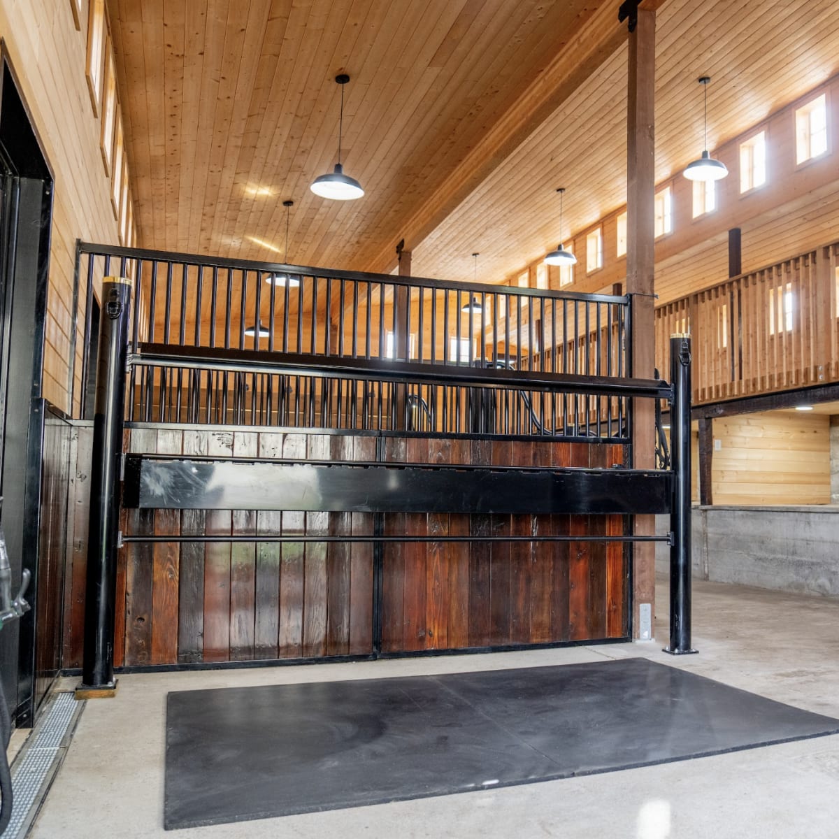 The interior of a spacious horse stable with wooden walls, high ceilings, and a central area for grooming and care.