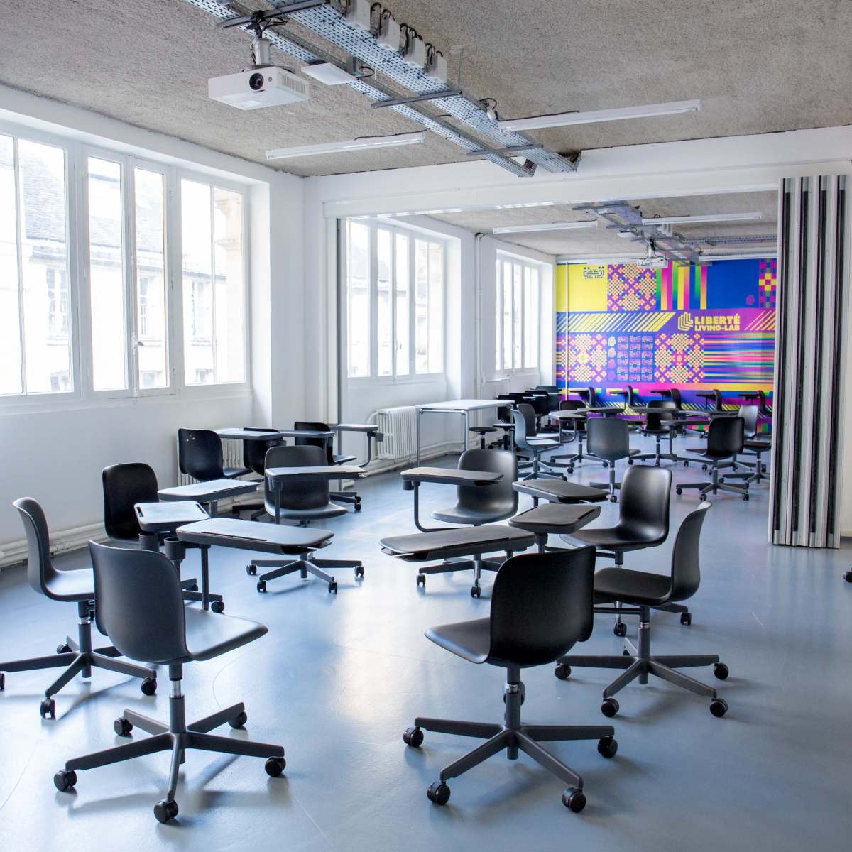 A modern classroom with movable black chairs and desks arranged for a collaborative learning environment.