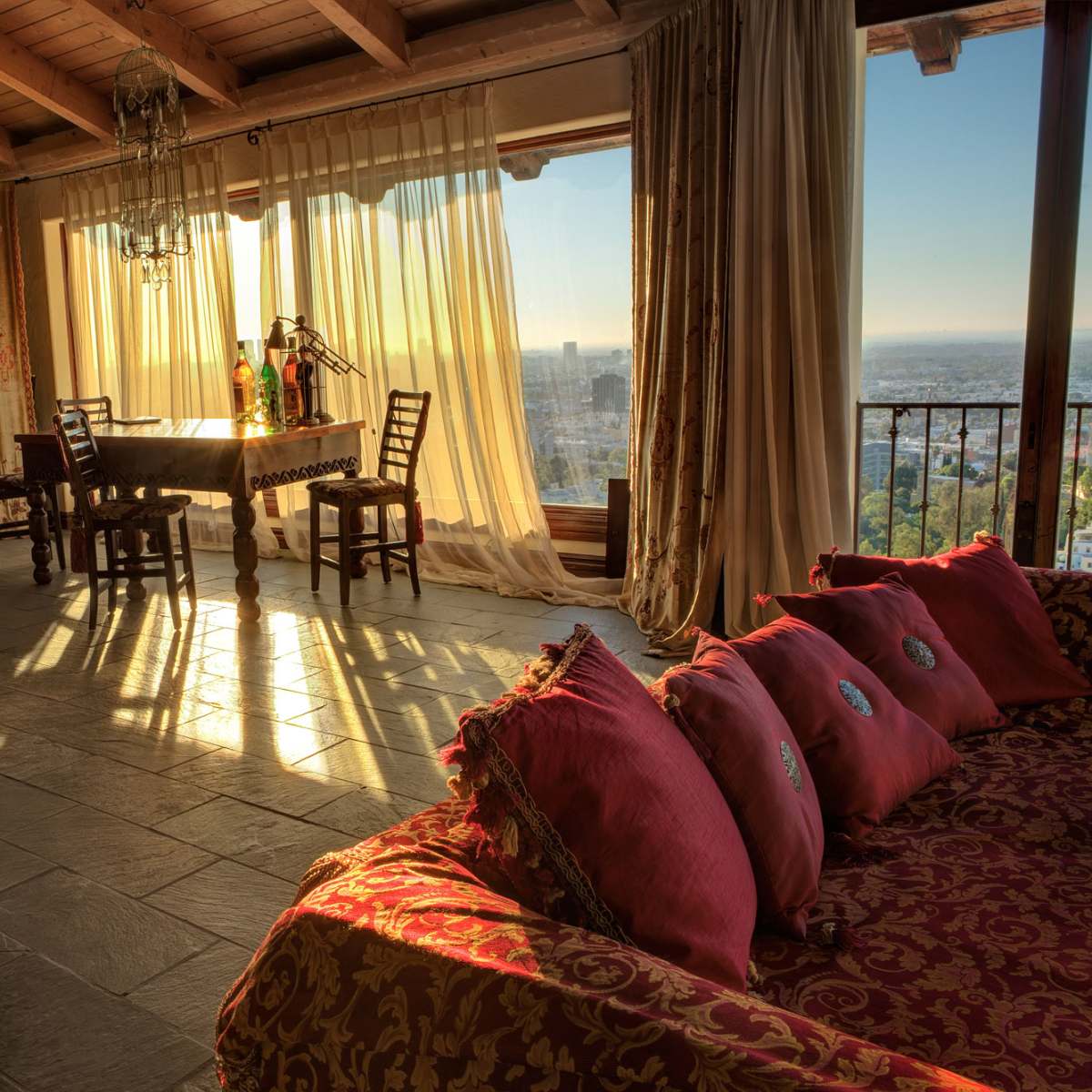 A sunlit room with a dining area featuring wooden chairs and a table, alongside a comfortable seating area with decorative pillows.