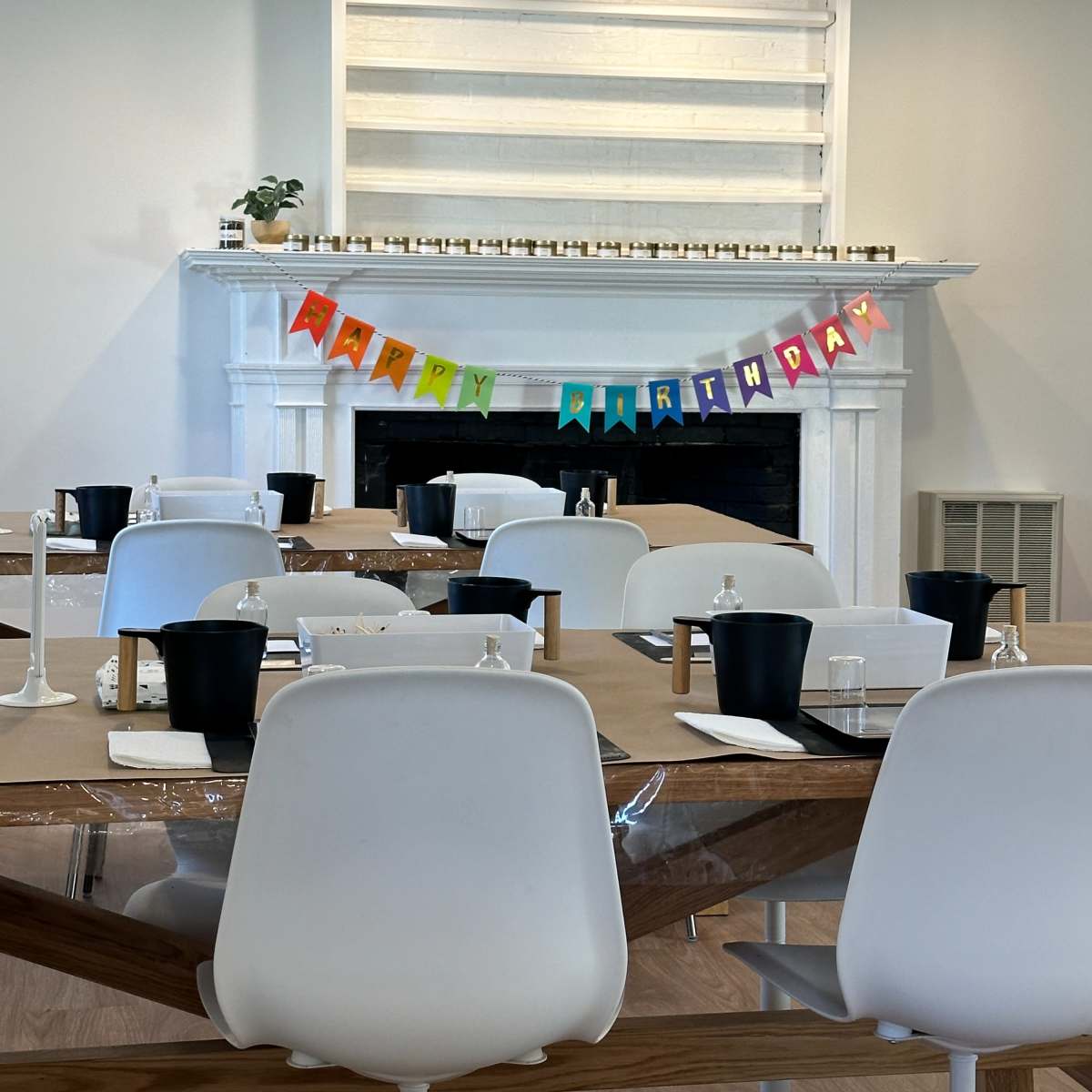 The room features a large table set for a birthday celebration, with a colorful "Happy Birthday" banner displayed above a decorative fireplace.