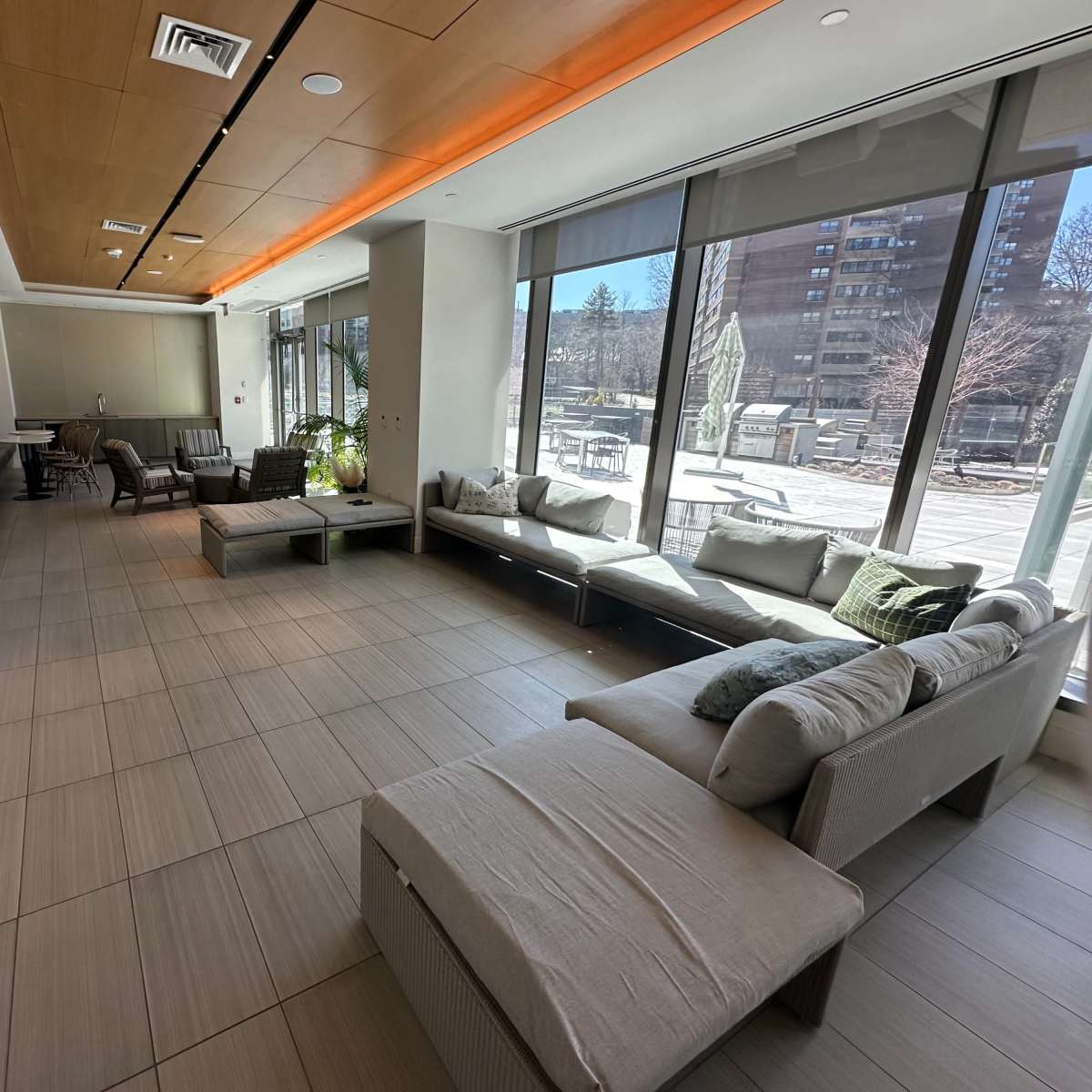 A spacious indoor lounge area with large windows, modern seating, and a TV on the wall.