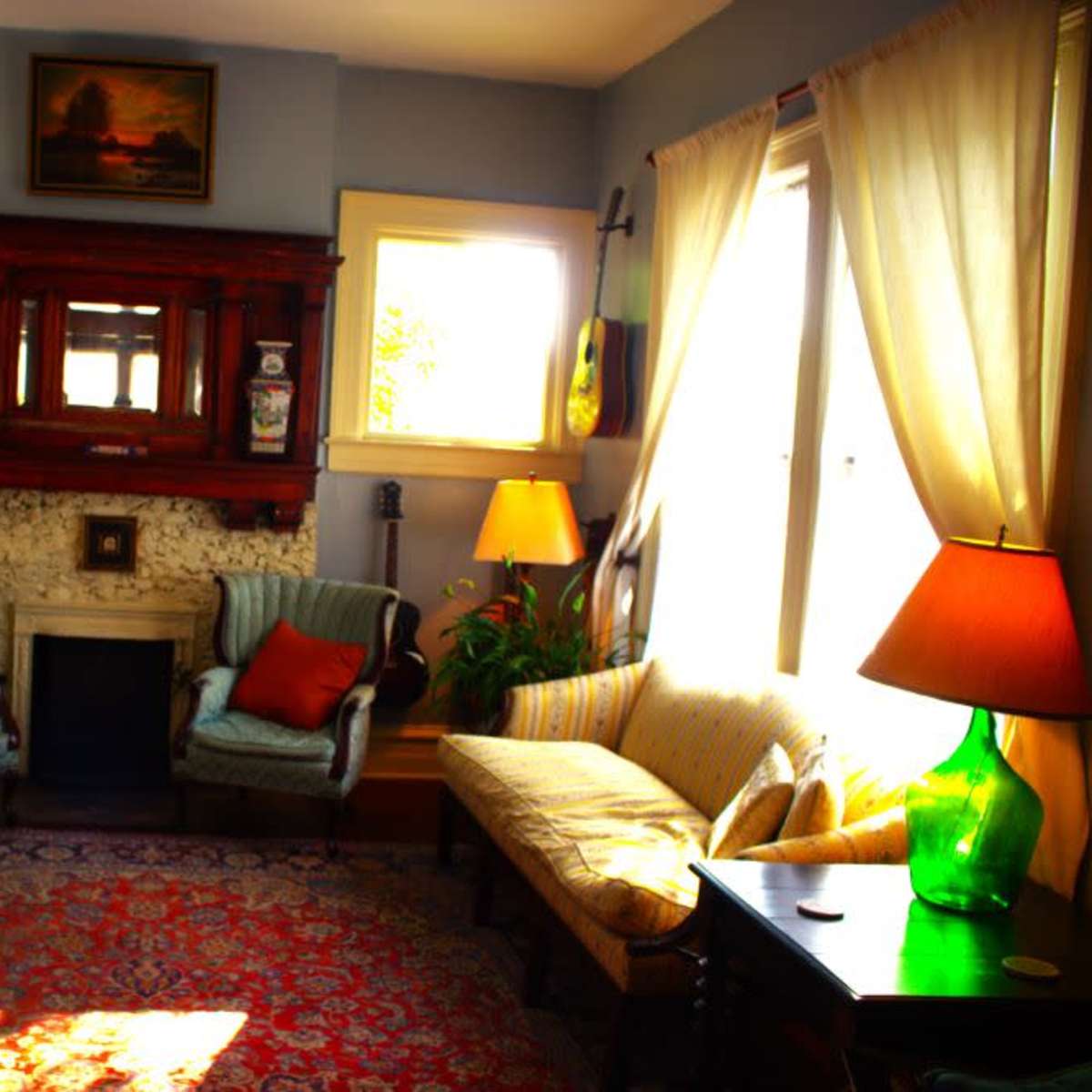 A cozy living room features two armchairs, a sofa, a fireplace with decorative elements, and large windows allowing natural light to fill the space.
