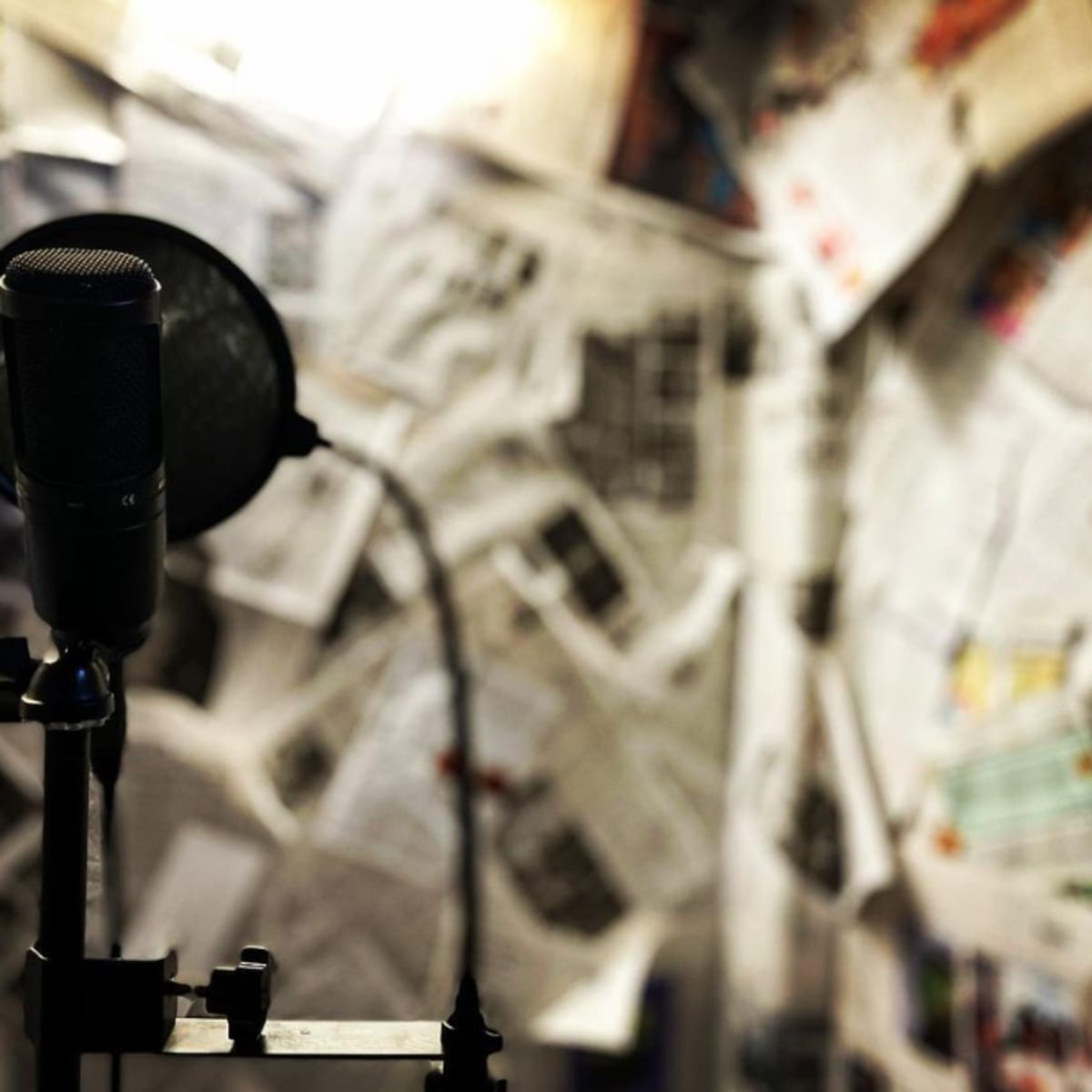 A microphone stands in front of a wall covered with newspapers.