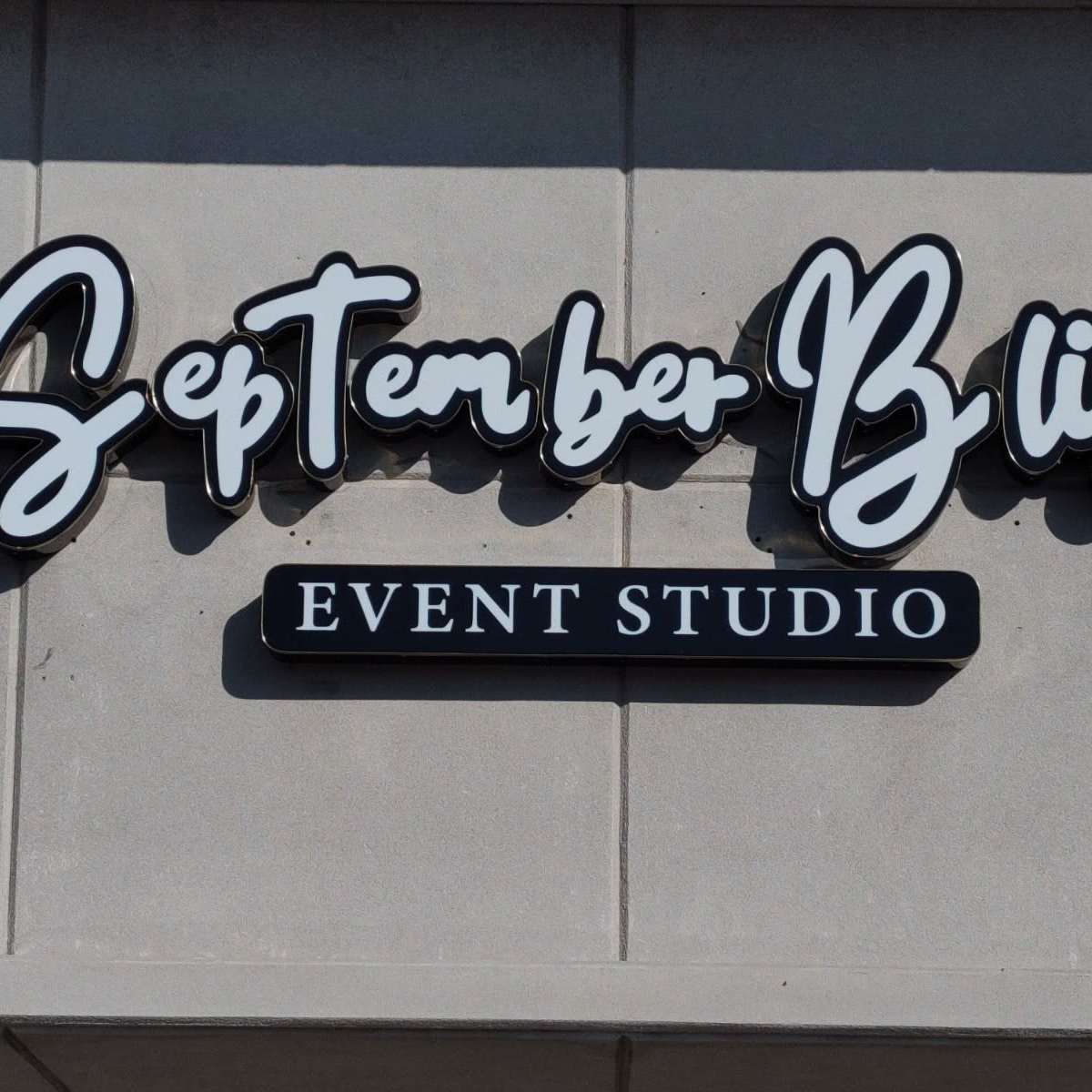 A sign for "September Bliss Event Studio" mounted on a grey wall.