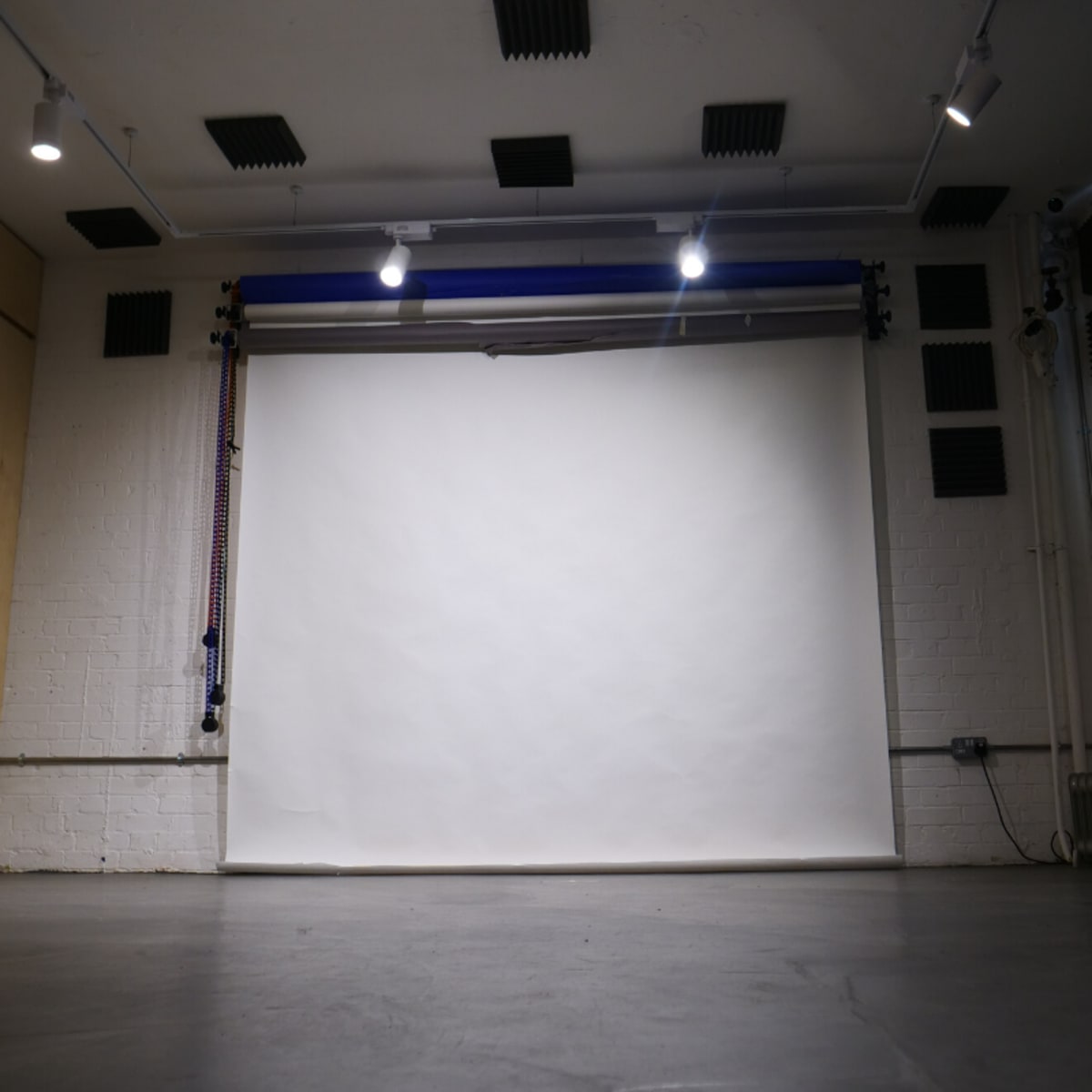 A blank white backdrop in a photography studio with wooden walls and overhead lights.