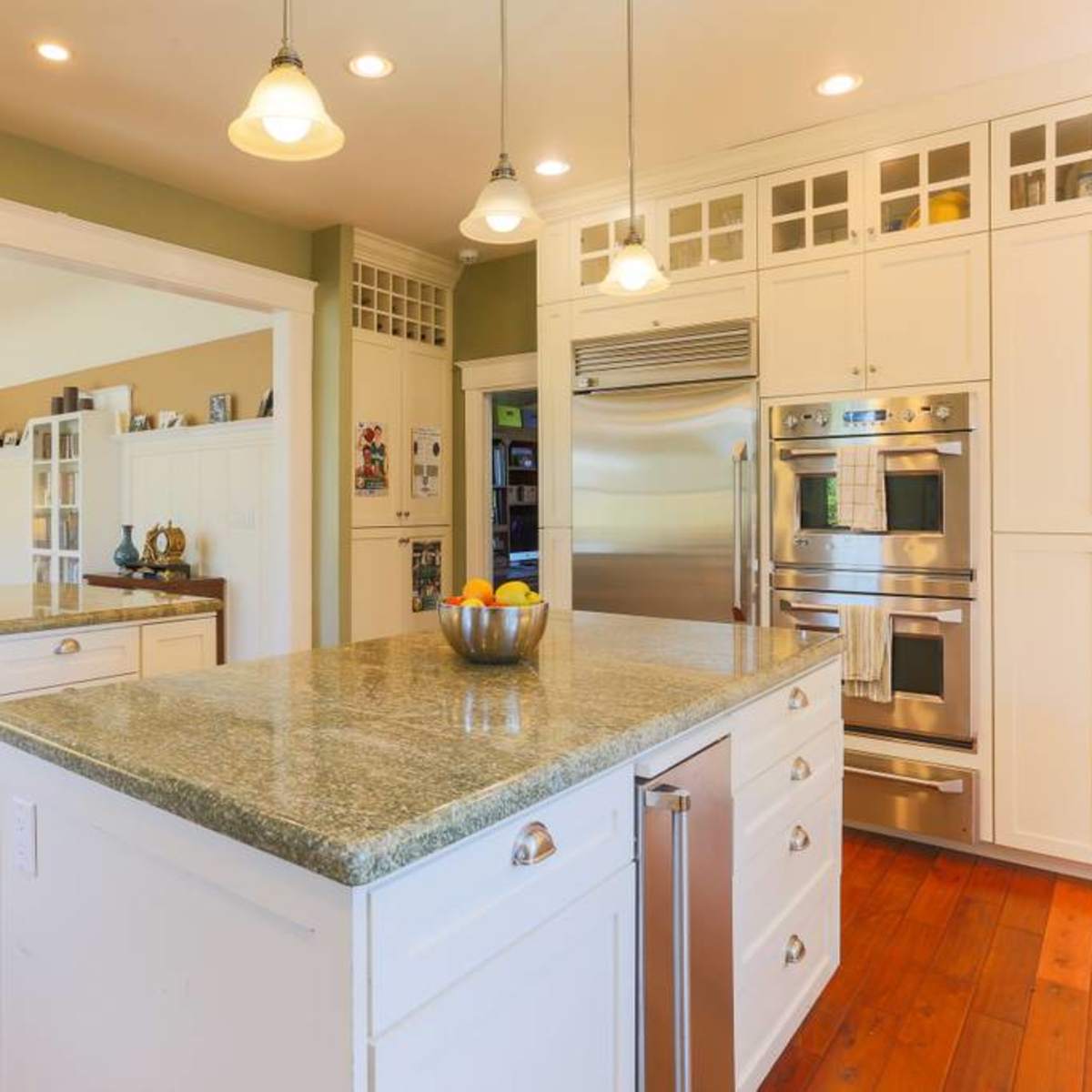 A spacious kitchen with white cabinets, a large granite island, and modern stainless steel appliances.