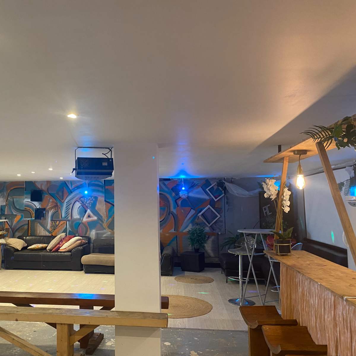 An indoor space with a mural on the wall, seating areas, and a bar setup.