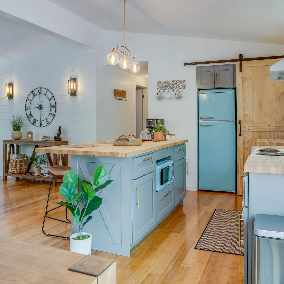 A modern kitchen featuring a blue retro-style refrigerator, wooden countertops, and a spacious island with a sink.