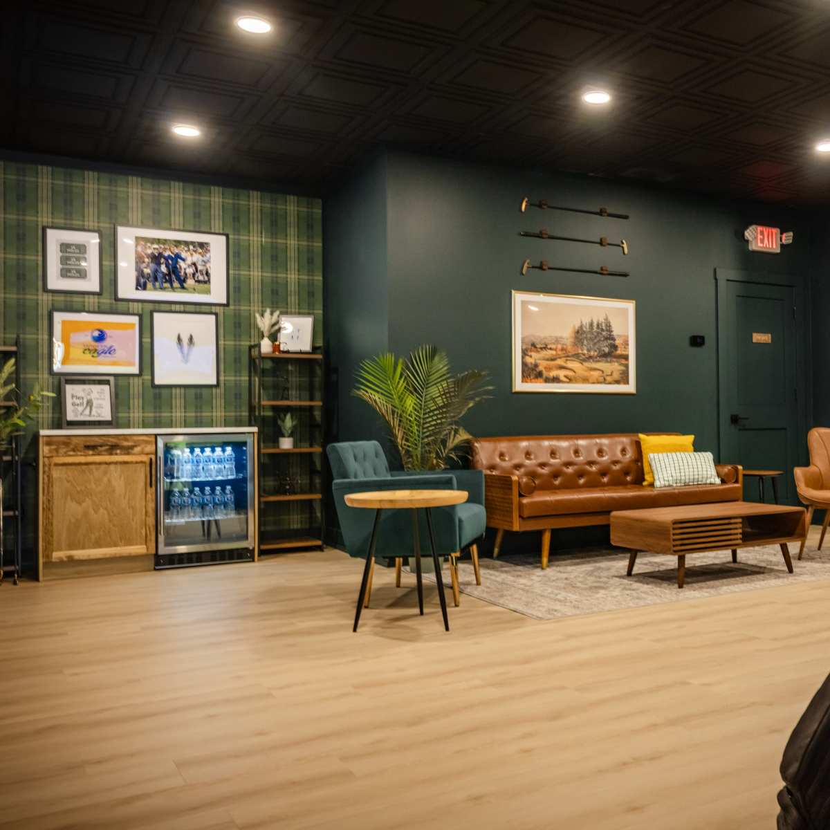 The scene features a modern lounge area with a mix of seating options, including a leather sofa, armchairs, and a coffee table, alongside a golf bag leaning against the wall.