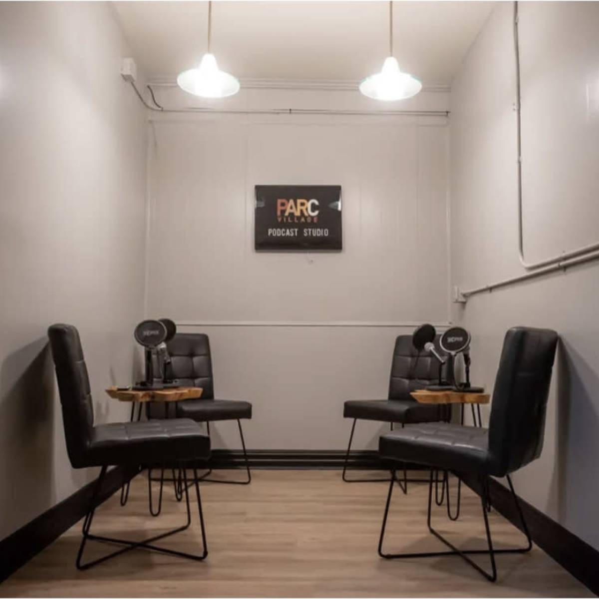 A small podcast recording studio with four black chairs and tables arranged around a central space, featuring a sign that reads "FARC Podcast Studio."