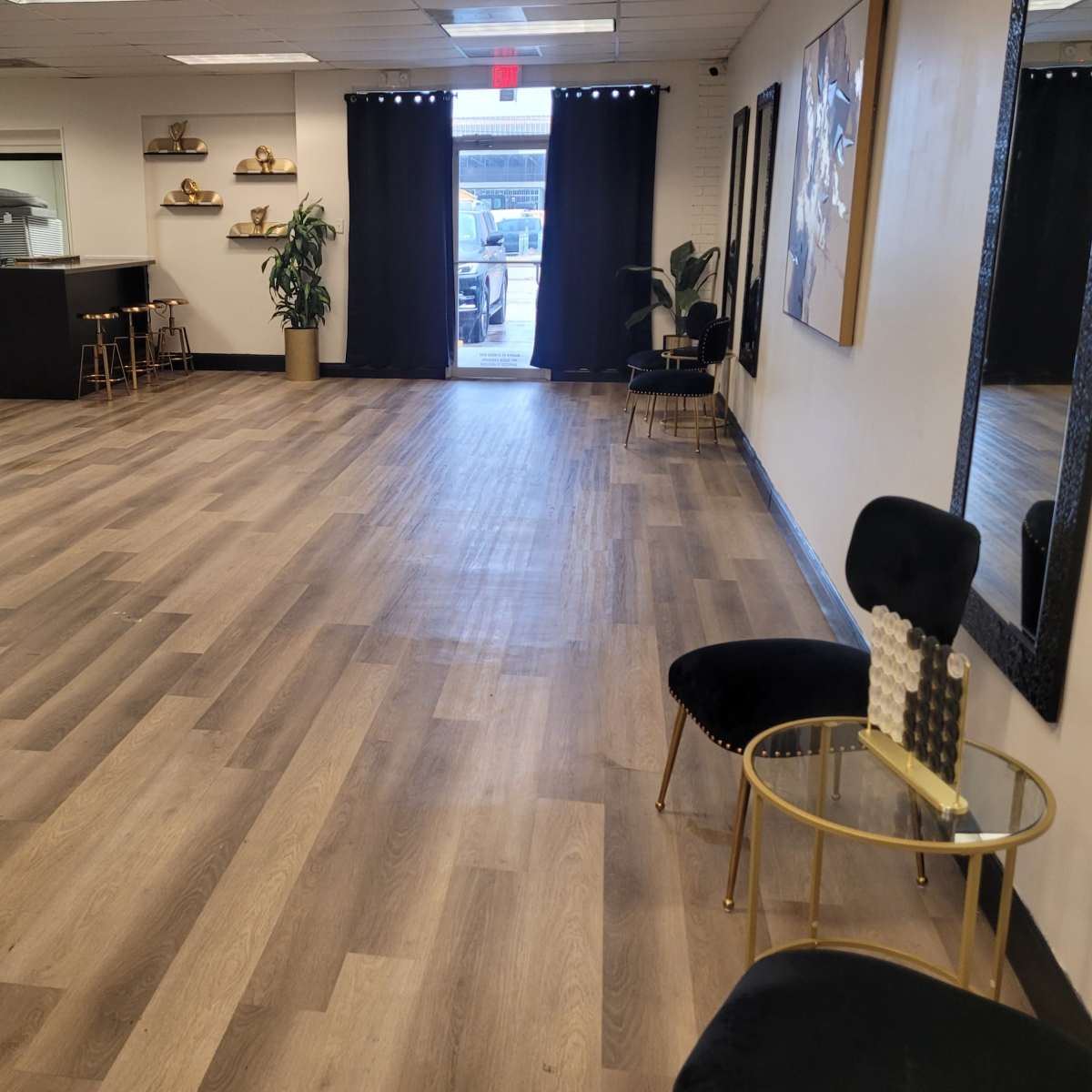 A spacious interior with wooden flooring, featuring two sofas, a small side table, and an exit door leading to an outdoor area.