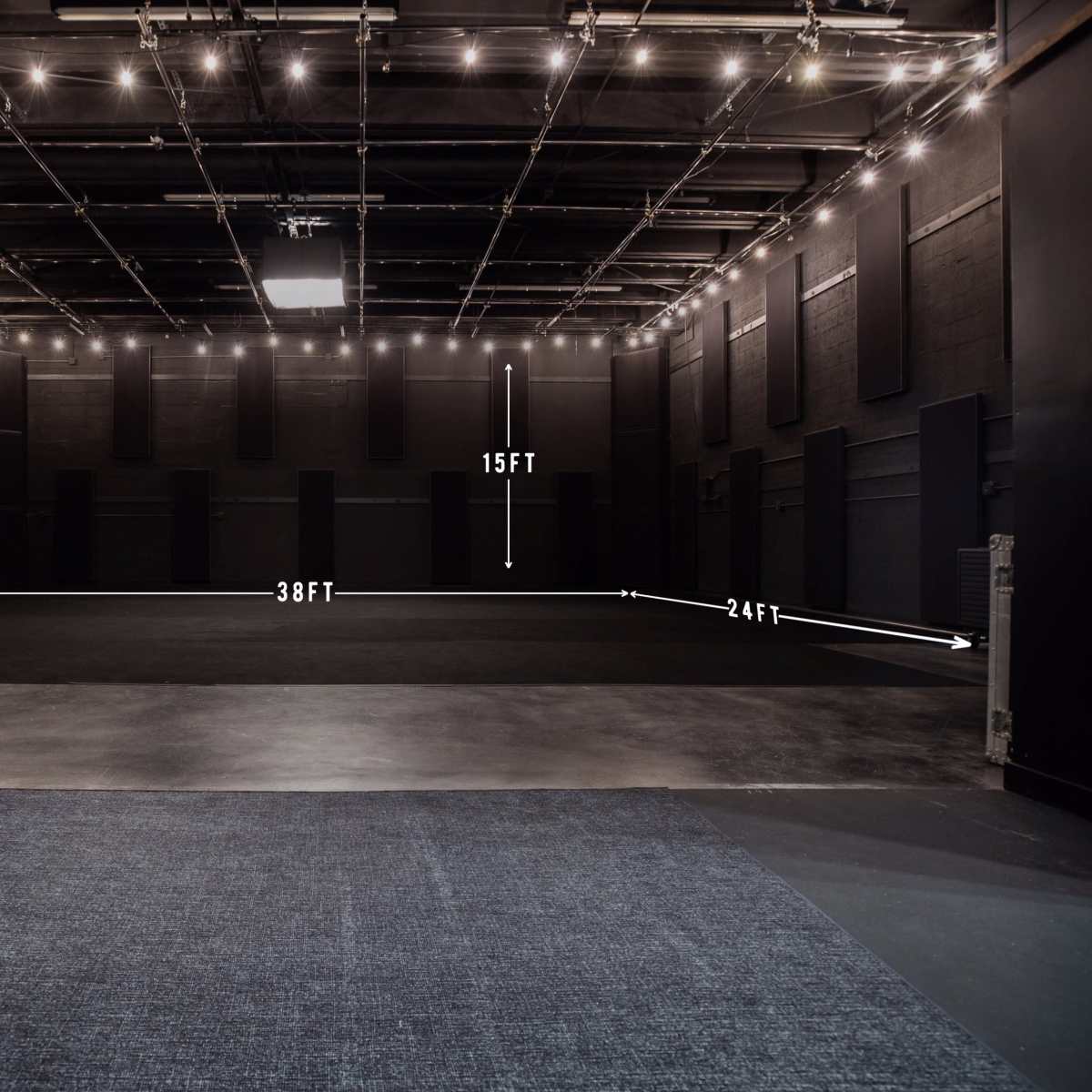 A spacious recording studio or performance space with a total area of 38 feet by 24 feet and a height of 15 feet, illuminated by overhead lights.