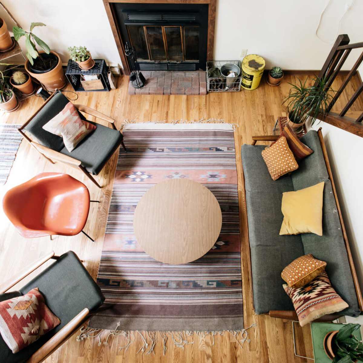 A cozy living room with a wooden floor, a round coffee table in the center, and comfortable seating arranged around a patterned rug.