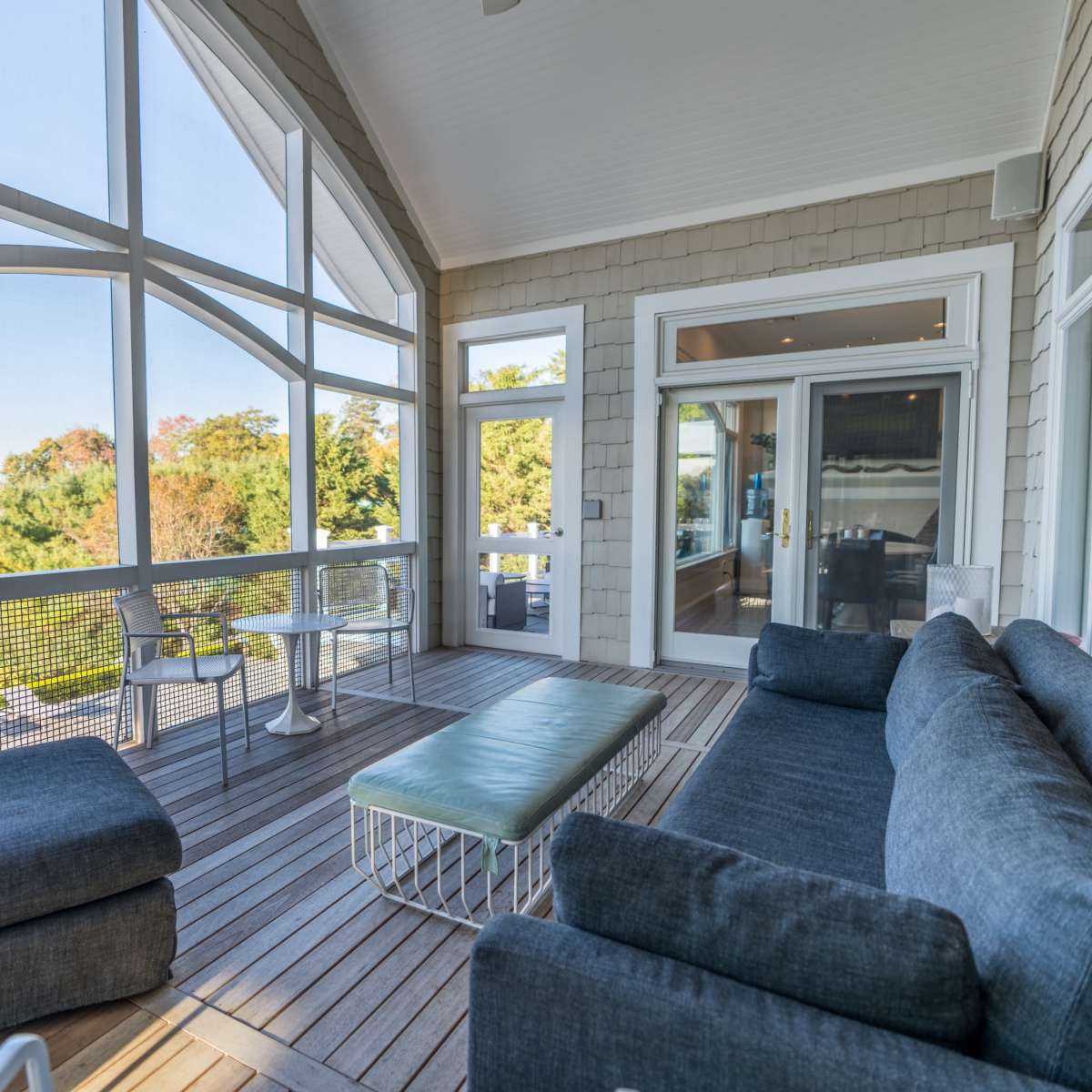 A modern outdoor seating area features a sectional sofa and a coffee table, overlooking a scenic view of the water and trees.