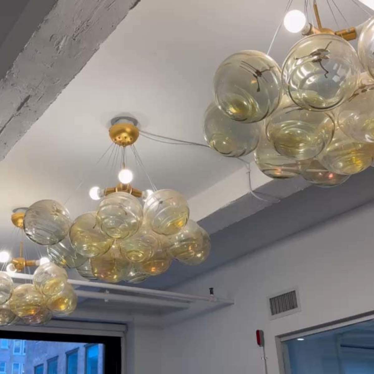 A modern ceiling light fixture composed of multiple clear glass globes arranged in a cloud-like formation.