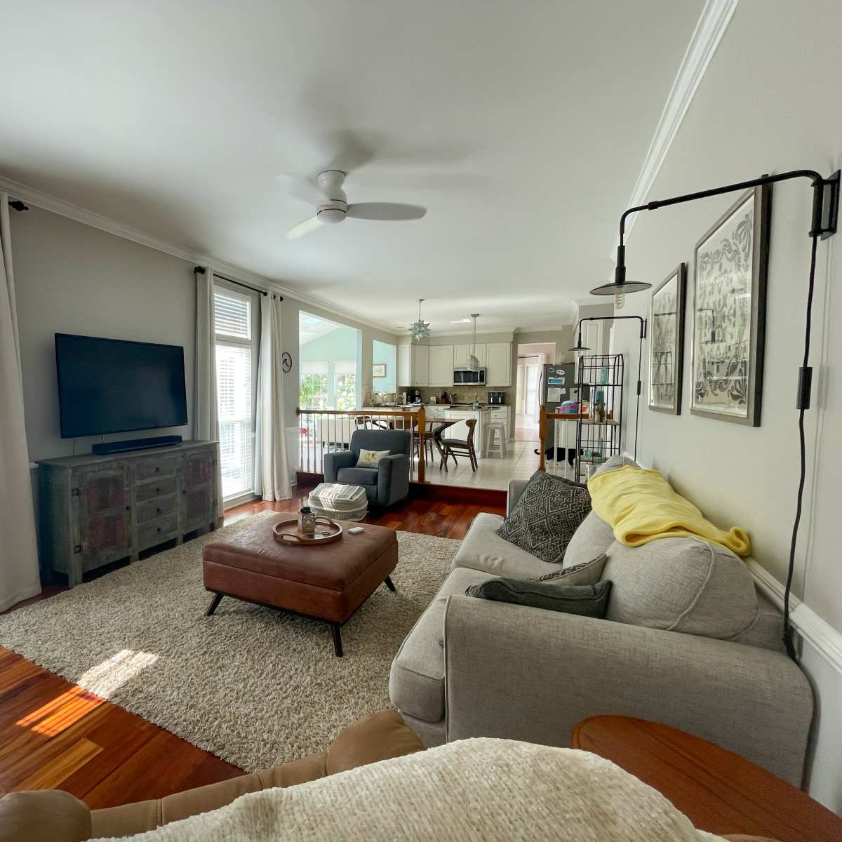 A living room with a sofa, TV, rug, and a view into a kitchen area.