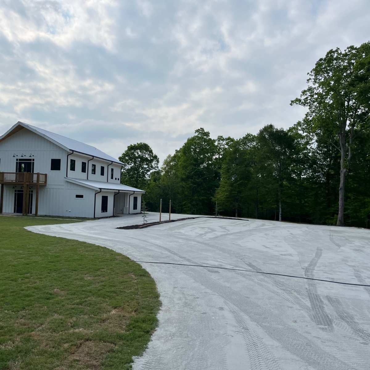 A modern two-story white building sits on a large, cleared lot with freshly paved gravel extending around it.