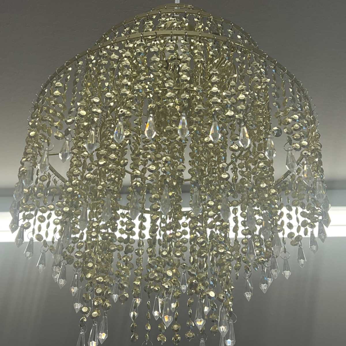 A gold-colored chandelier adorned with hanging crystal droplets.