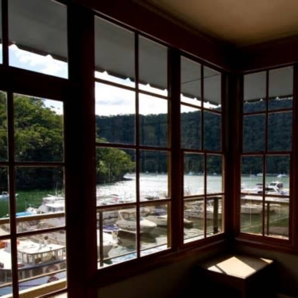 A view from a window overlooking a marina with boats docked along a green, wooded shoreline.