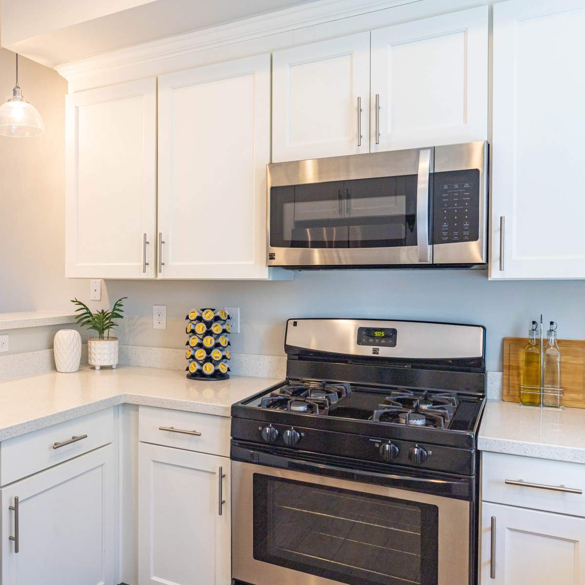 A modern kitchen featuring white cabinets, a stainless steel microwave and oven, and a light-colored countertop.