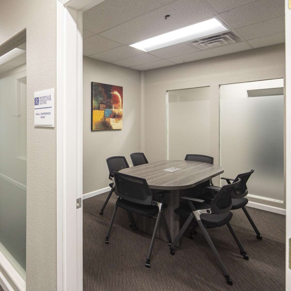 A well-lit hallway leading to a conference room with a large table and chairs.