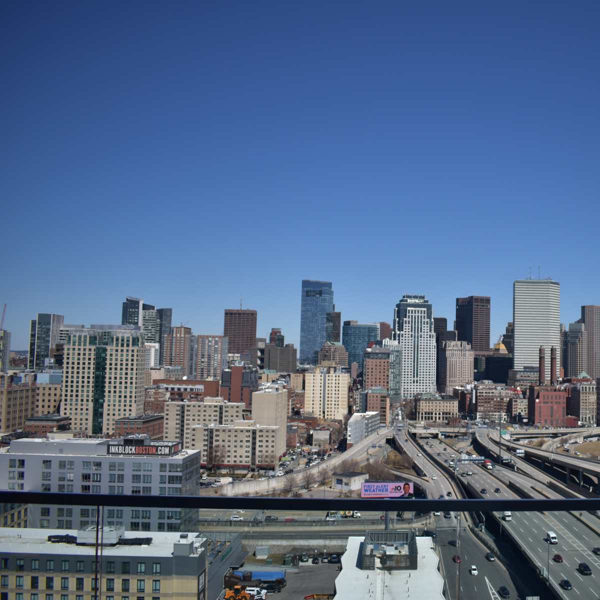 A clear view of a city skyline featuring modern skyscrapers and highways under a blue sky.