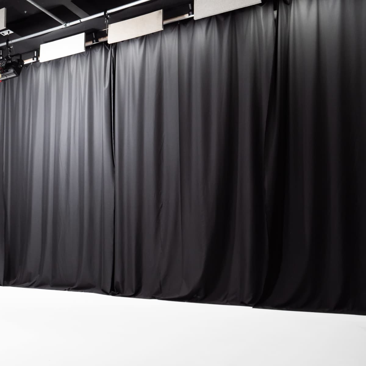 A photo studio with black curtains and a white floor.