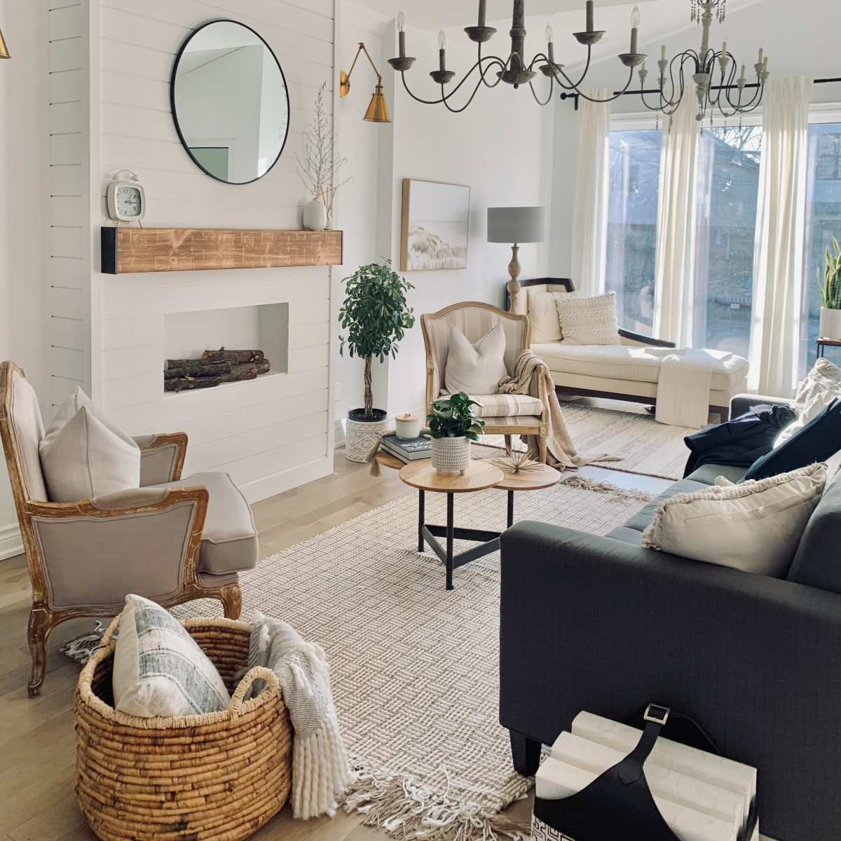 A modern living room with a fireplace, large windows, and a mix of comfortable seating arrangements.