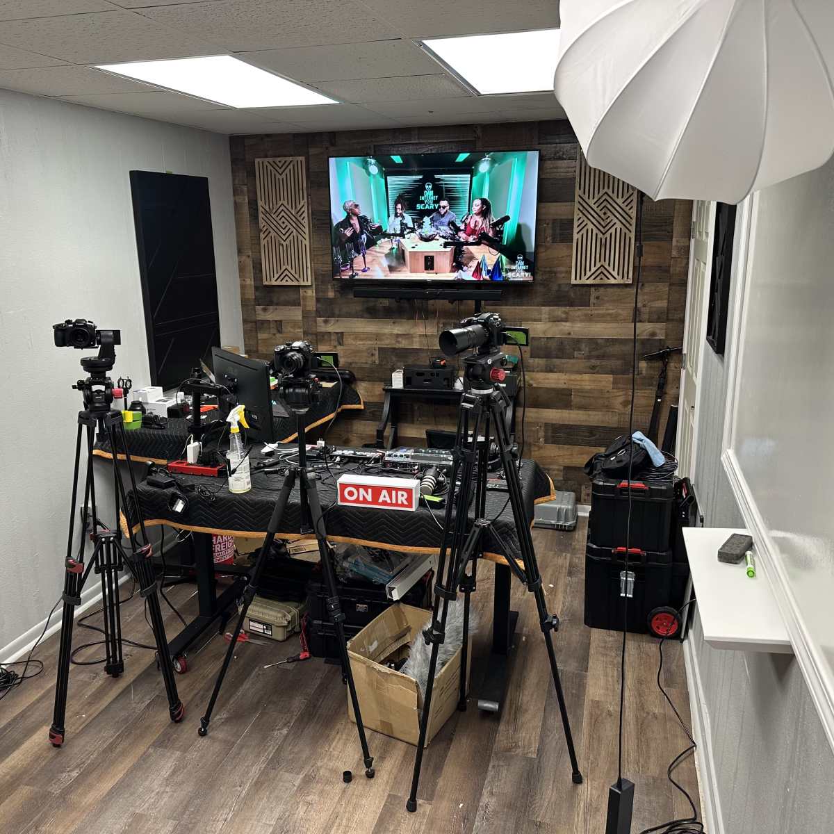 A recording studio equipped with multiple cameras, a large monitor displaying a live set, and a table set up for a broadcast.