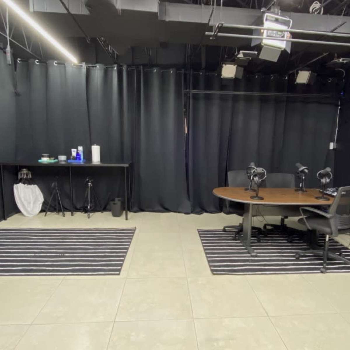 A dimly lit studio space with black curtains, a table and chair, and two cameras set up on tripods.
