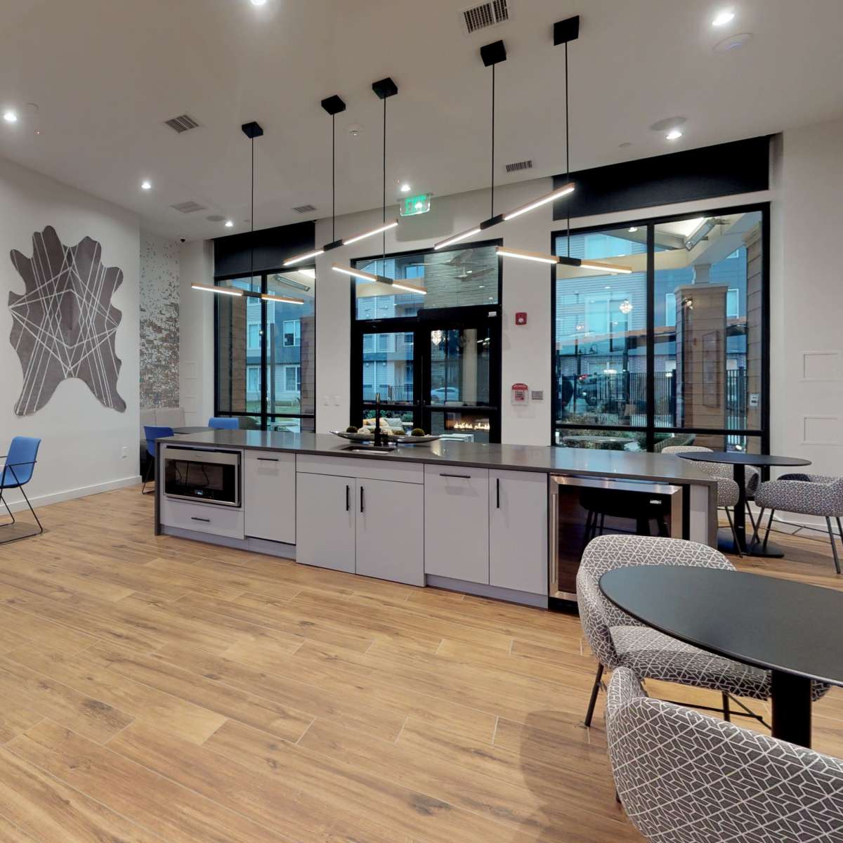A modern communal space with kitchen amenities, seating areas, and large windows.